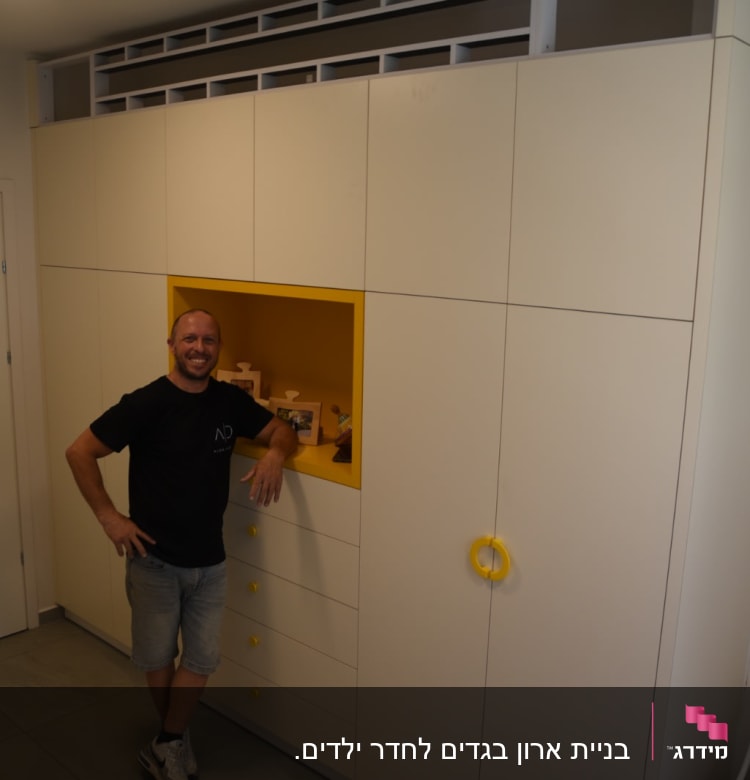 נגר עומד ליד ארון עם ידיות צהובות